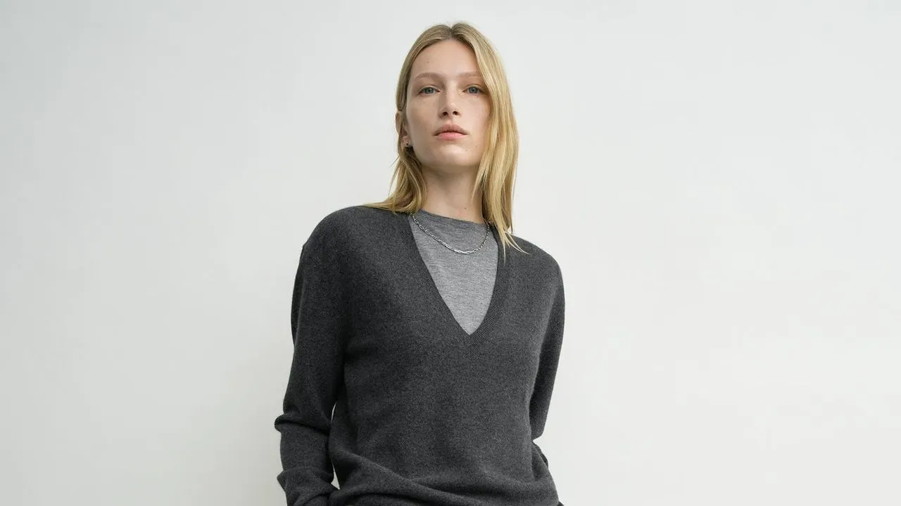 A man wearing a V-neck sweater, styled casually with a pair of jeans.