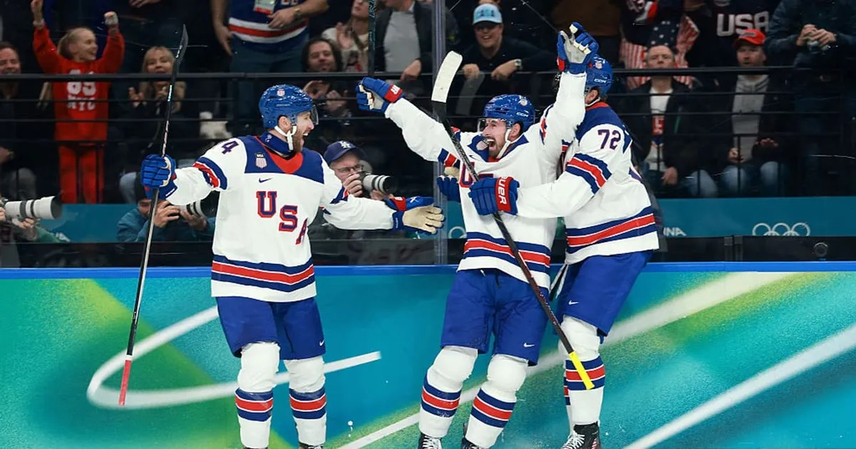 Dylan Larkin celebrating after scoring a goal for Team USA in the 2026 Winter Olympics men's hockey semifinal, teammates skating nearby and the Slovakia goalie in the crease.